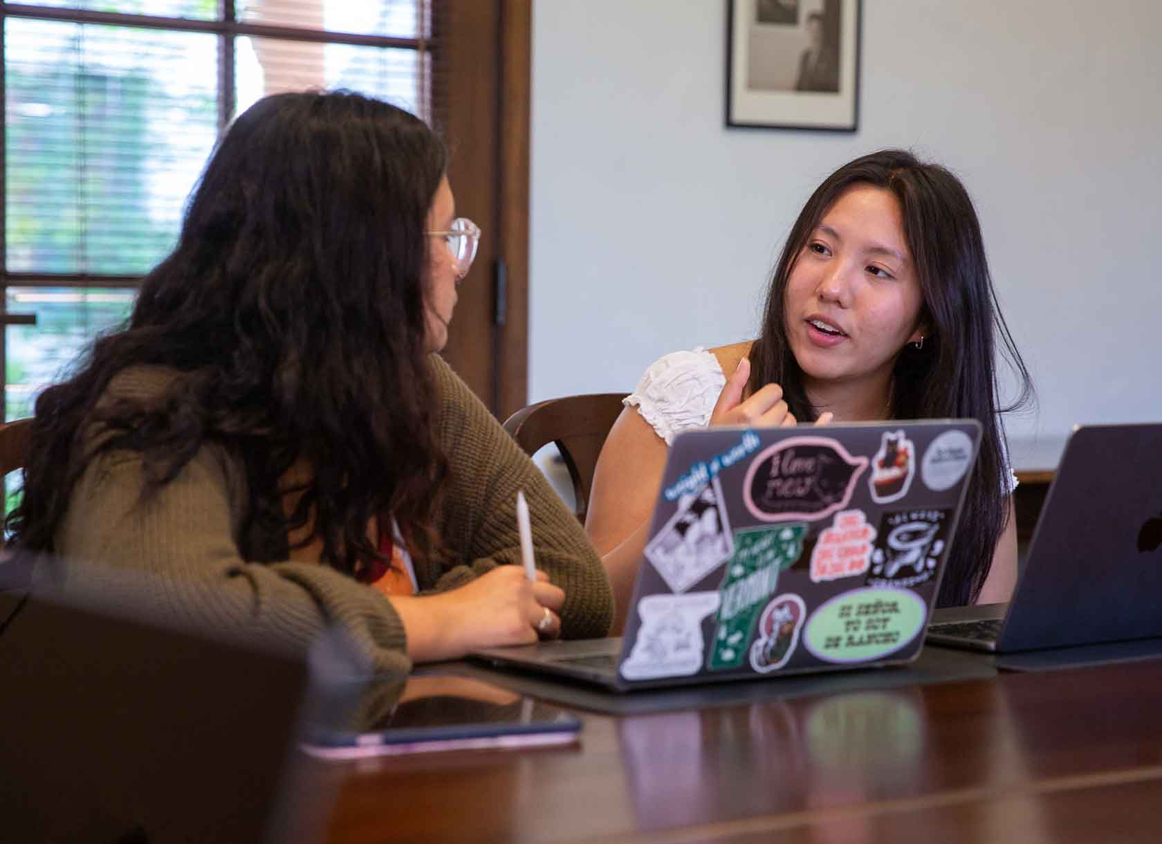 Two student in conversation with a laptop in front of them