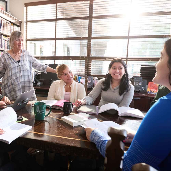 Faculty member conversing with students around a table
