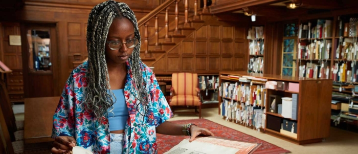 Student in Denison Library looking a a book from the special collections