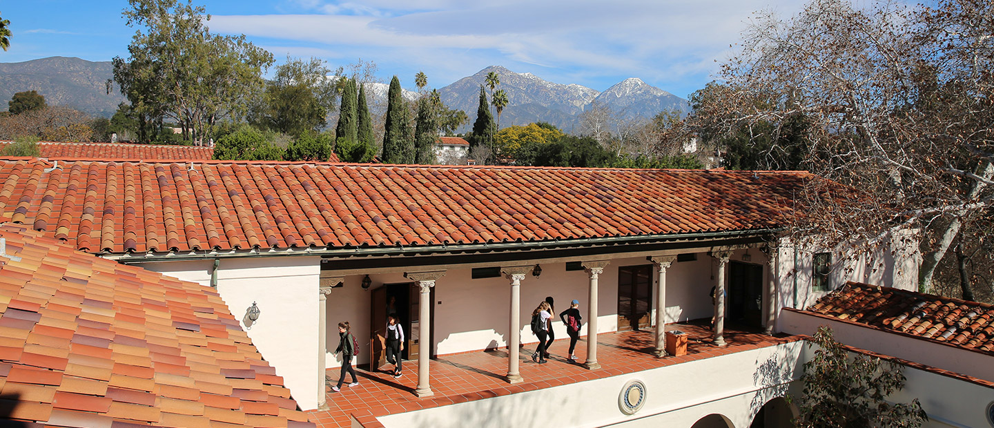 Image of students walking from class through an outdoor hallway with terracotta tiles and roof.