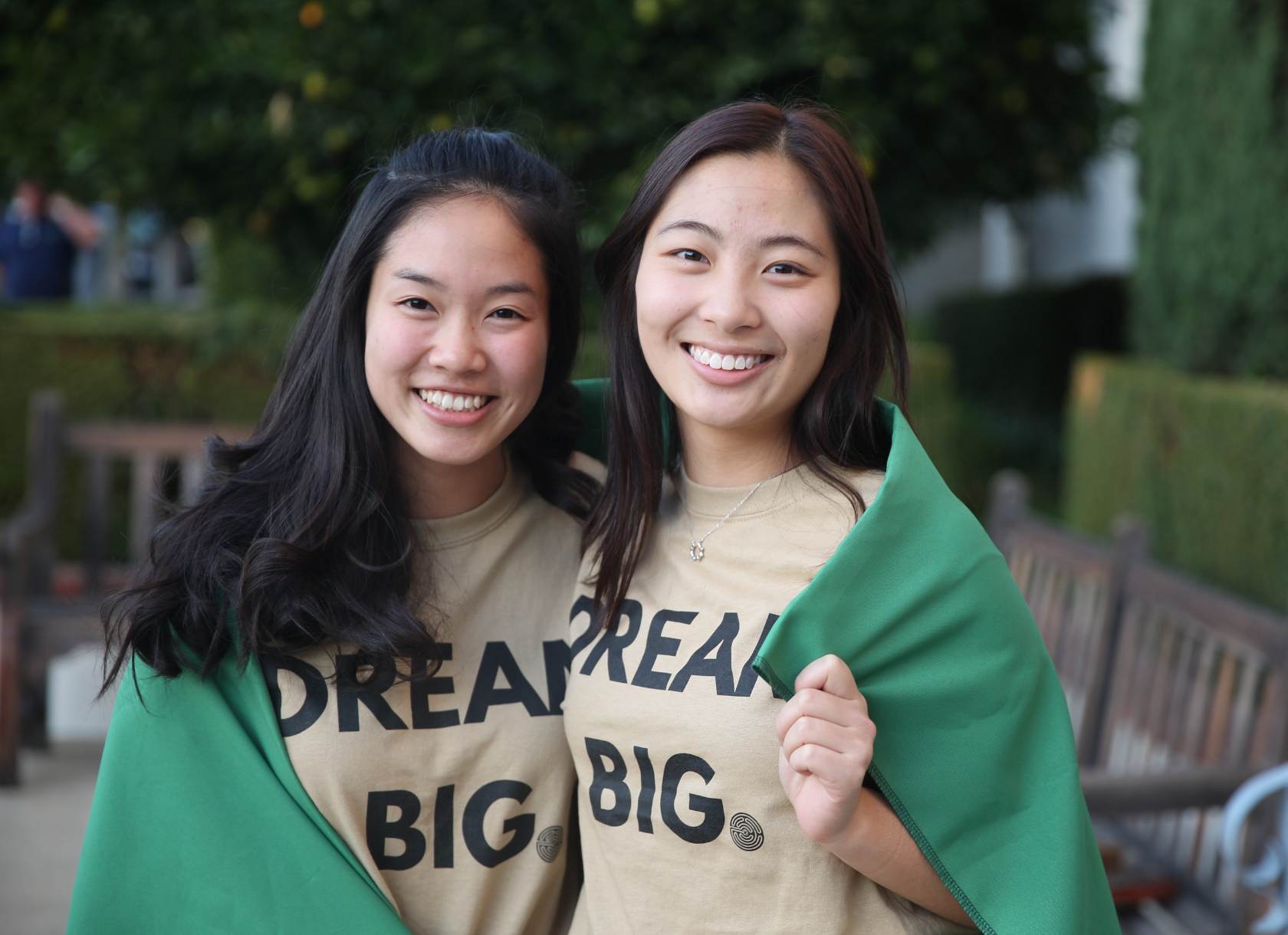 Two students wearing shirts that say dream big with cape around them
