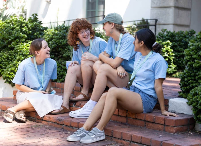 Four Scripps students on move-in day sitting on steps smiling at each other