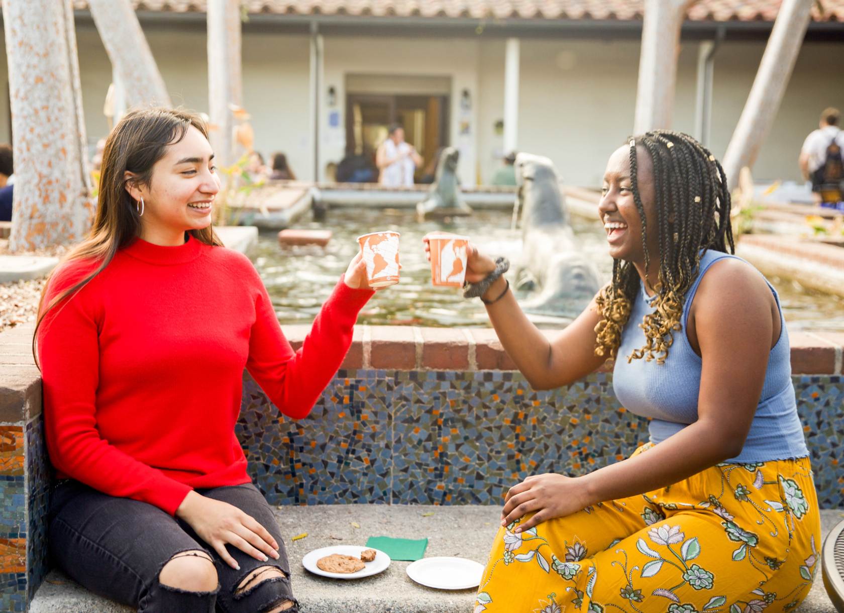 Two Scripps students facing each other holding cups and smiling