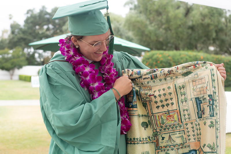 Student with cap and gown holding Scripps blanket