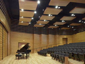 A music auditorium with a grand piano and rows of seats.