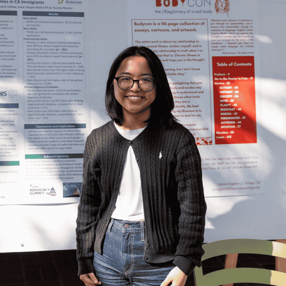 A young Asian woman with glasses stands in front of her poster