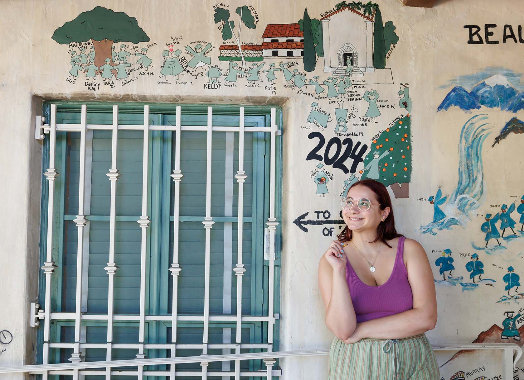 Photograph of Corinne Stevens standing in front of her design on the Graffiti Wall.