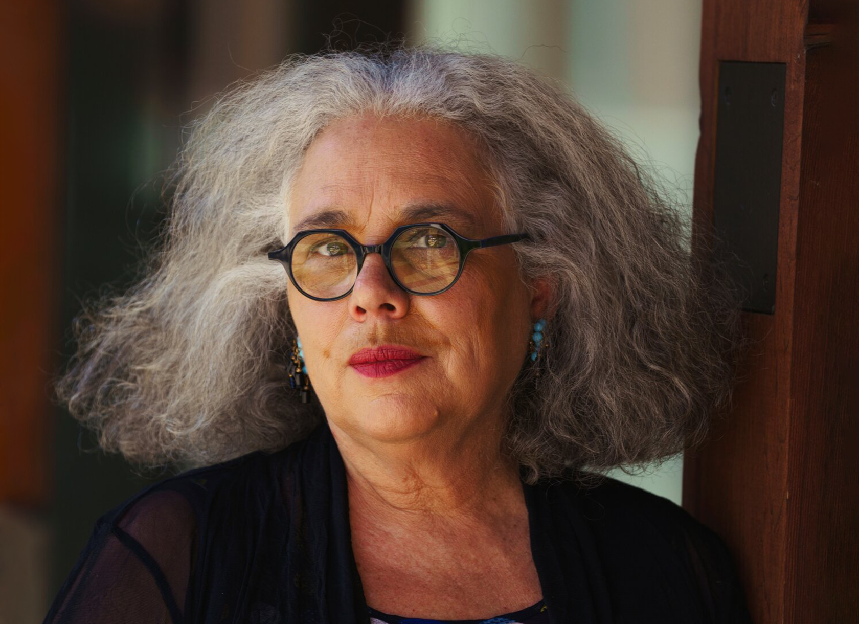 Portrait of Alison Saar '78, renowned artist and alum of Scripps College in Southern California. She is a black woman with gray, shoulder-length hair and glasses.