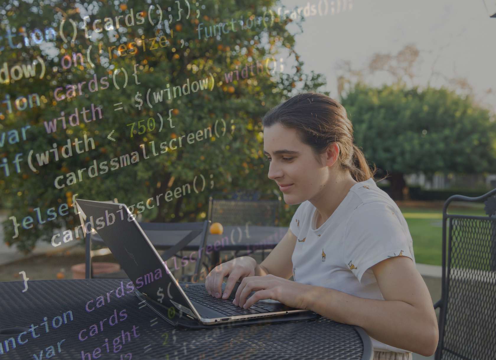 A Scripps student works on a computer with an overlay of programming language text
