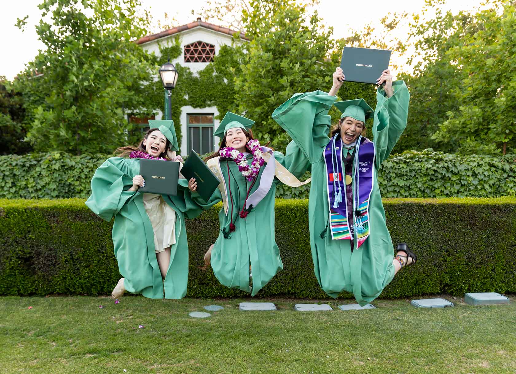 Members of the Scripps College Class of 2023 jump with their diplomas