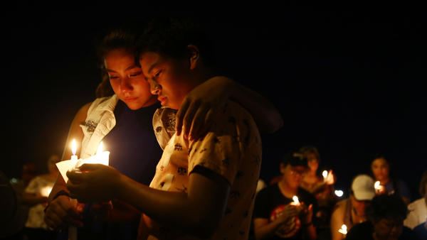 A young man and woman holding candles in a crowd of people holding candles.