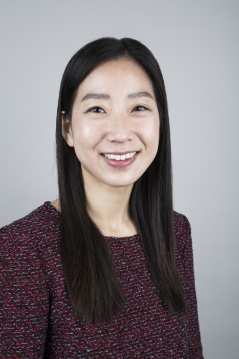 An Asian woman with long black hair and a maroon sweater smiling.