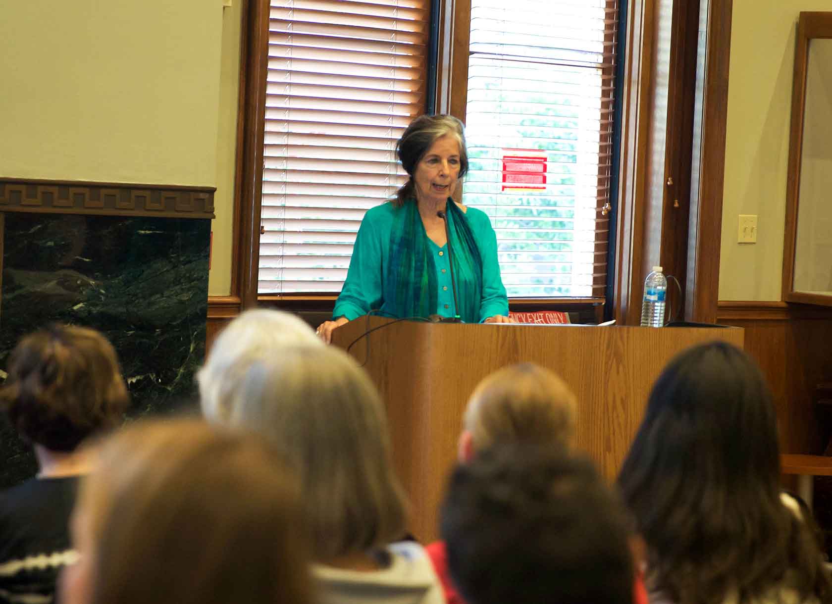 Professor Emerita Gayle Greene reads from a podium