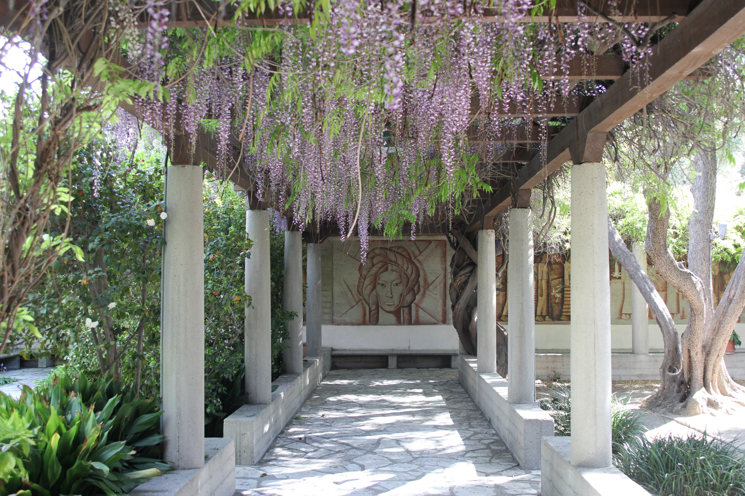 A garden walkway leading to a mural featuring a woman's face.