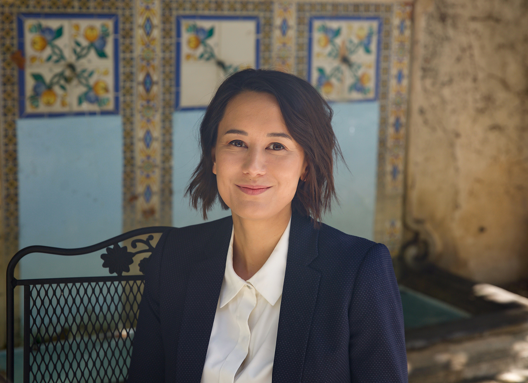 A woman with short brown hair wearing a blazer and dress shirt smiling.