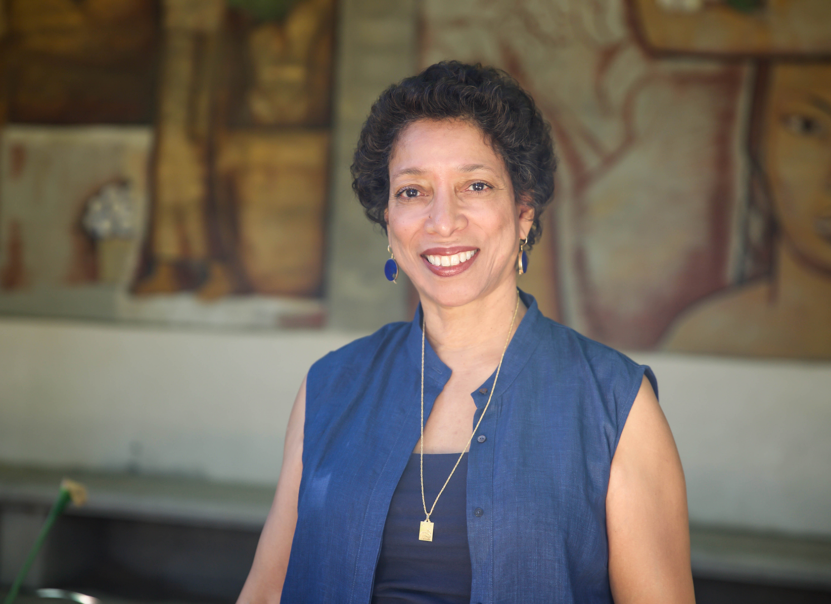 Close-up portrait of short-haired Black woman in sleeveless blue blouse