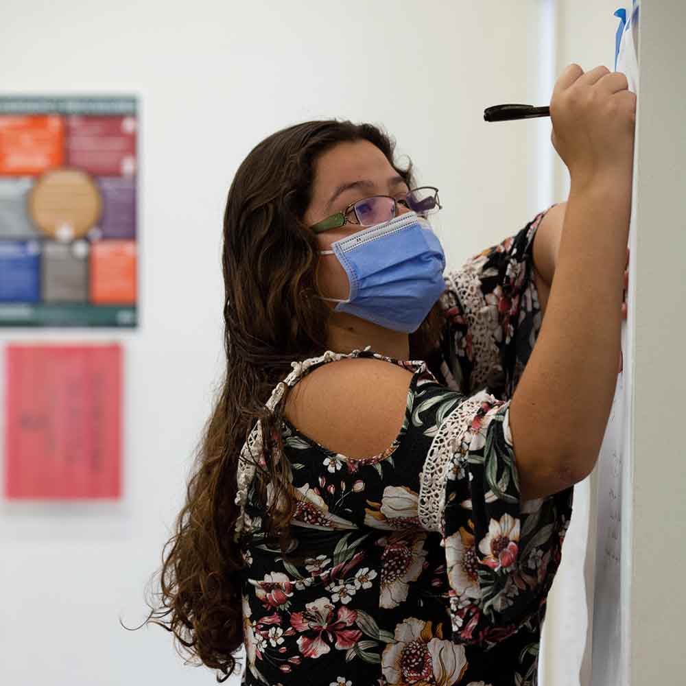 A Scripps College Academy participant writes on a posterboard