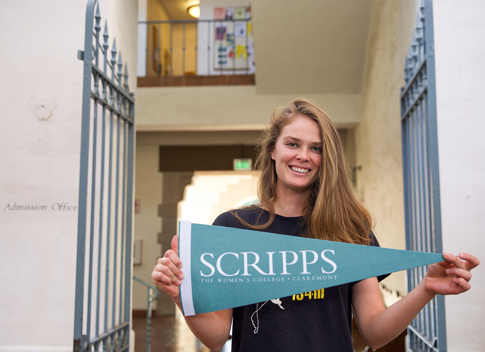 A white young woman with brown hair holding a Scripps College banner.