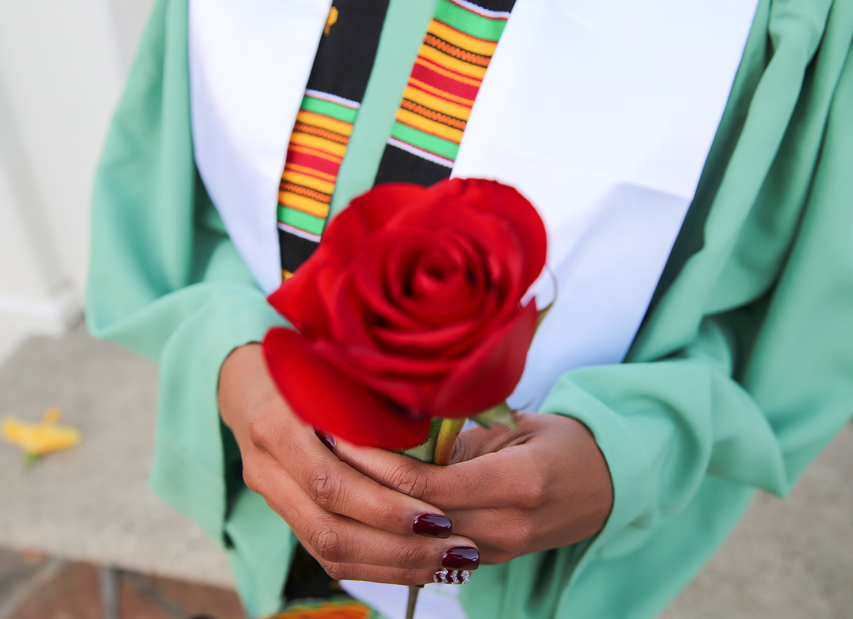 Close-up photo of a Scripps College graduate holding a rose