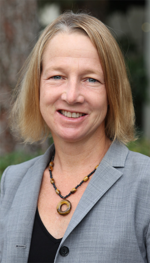 A white woman with short blond hair wearing professional clothing.