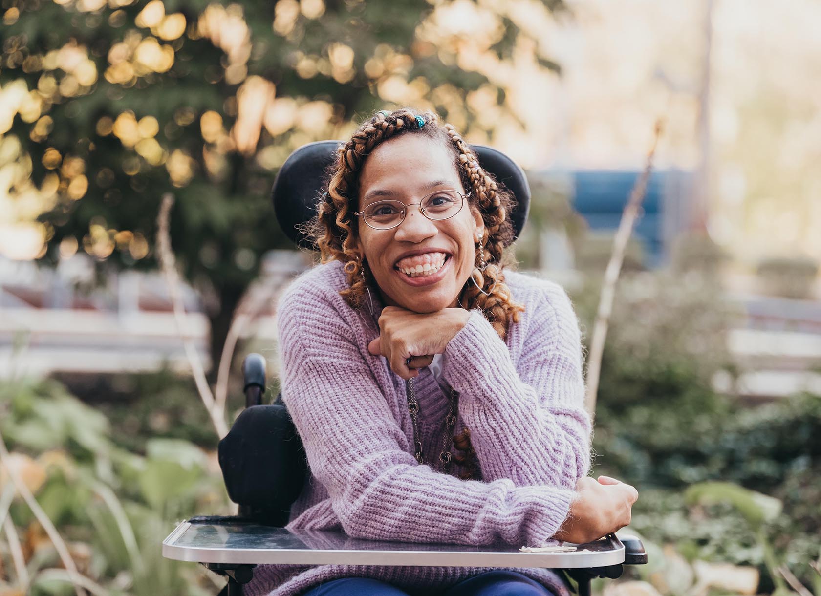 Photograph of Allison Thompkins, a Black woman with glasses in a purple sweater. She is smiling.