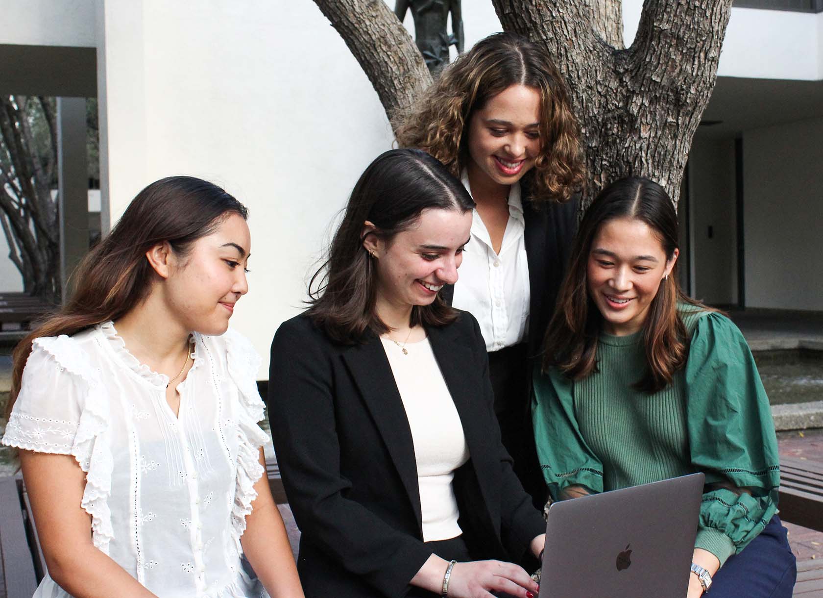 Four members of the Scripps Student Investment fund looking at a laptop together.
