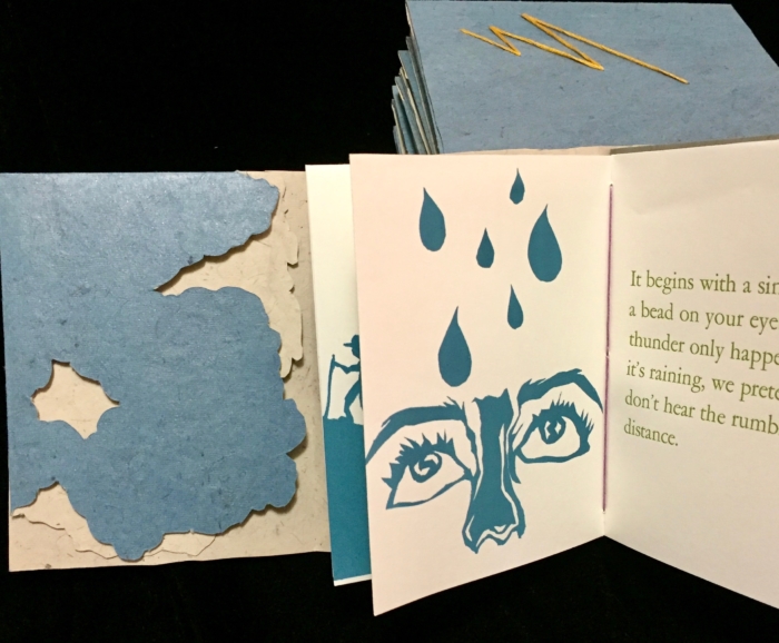 A blue handmade book cover next to an open copy of the same book.