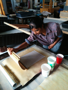 A brown woman with black hair making paper.