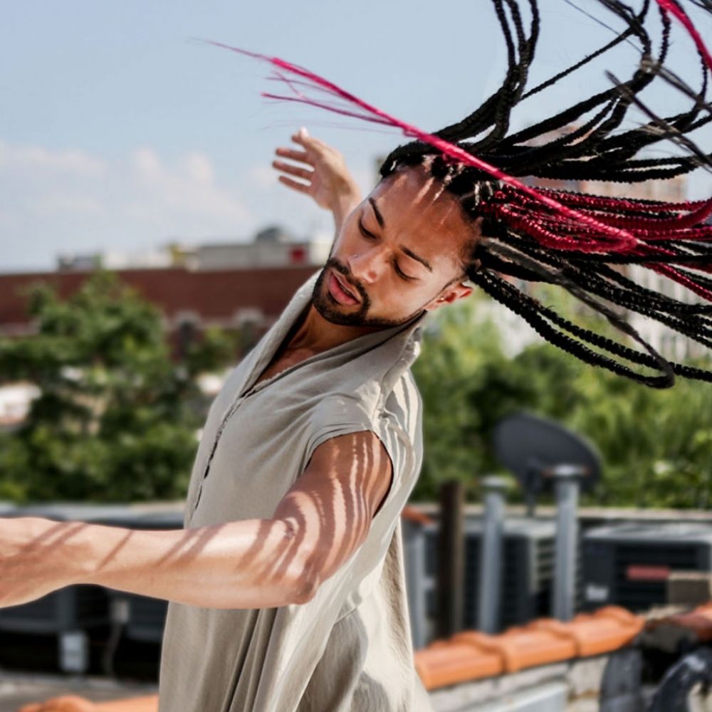 Abdiel Jacobsen, a Black person, spins with their braids catching in the wind.
