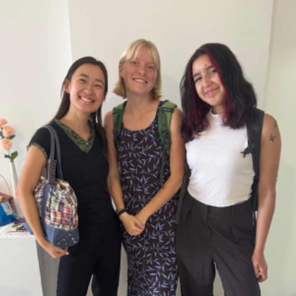 Three female students stand together, smiling