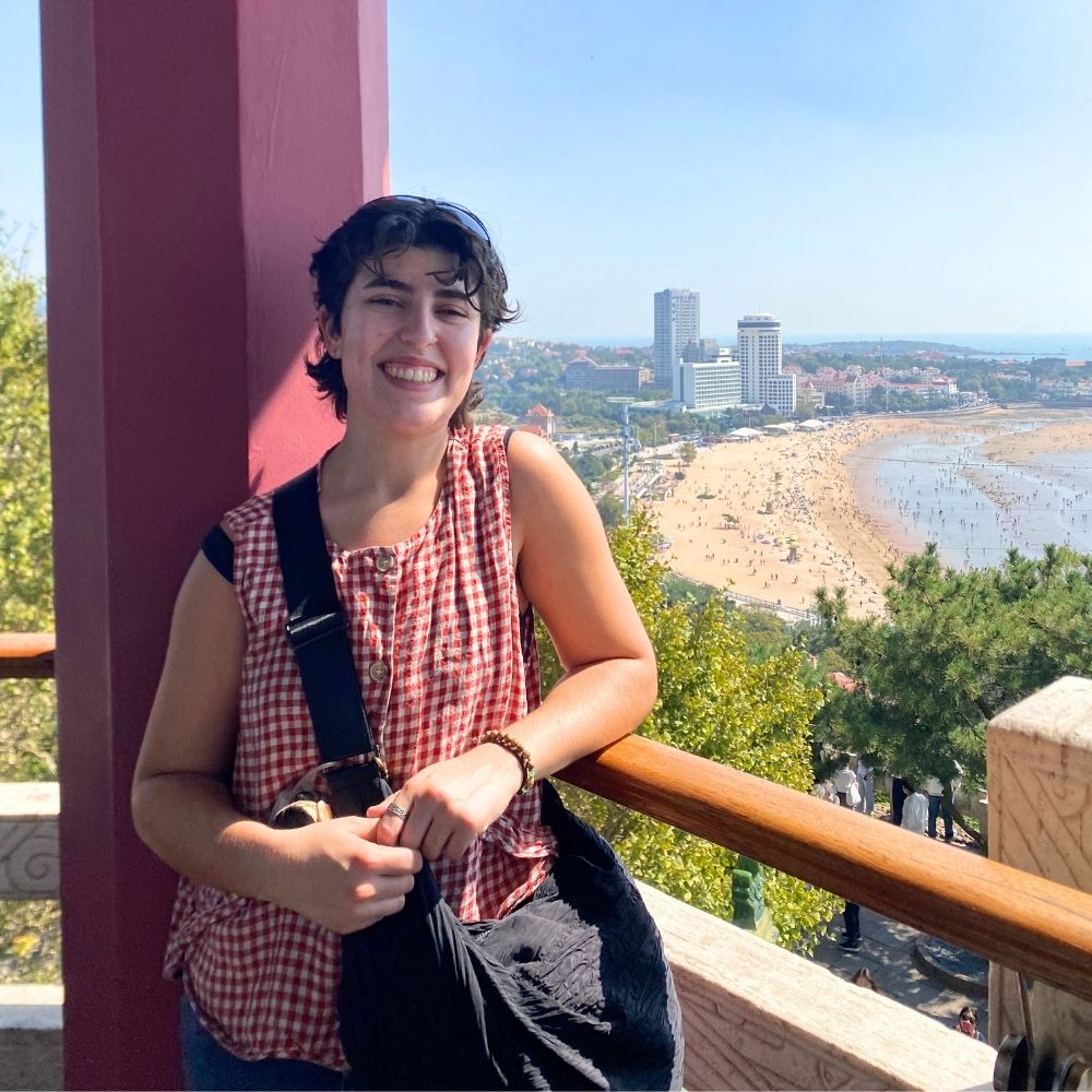 Malena Sparano smiles on balcony overlook sea in Asia