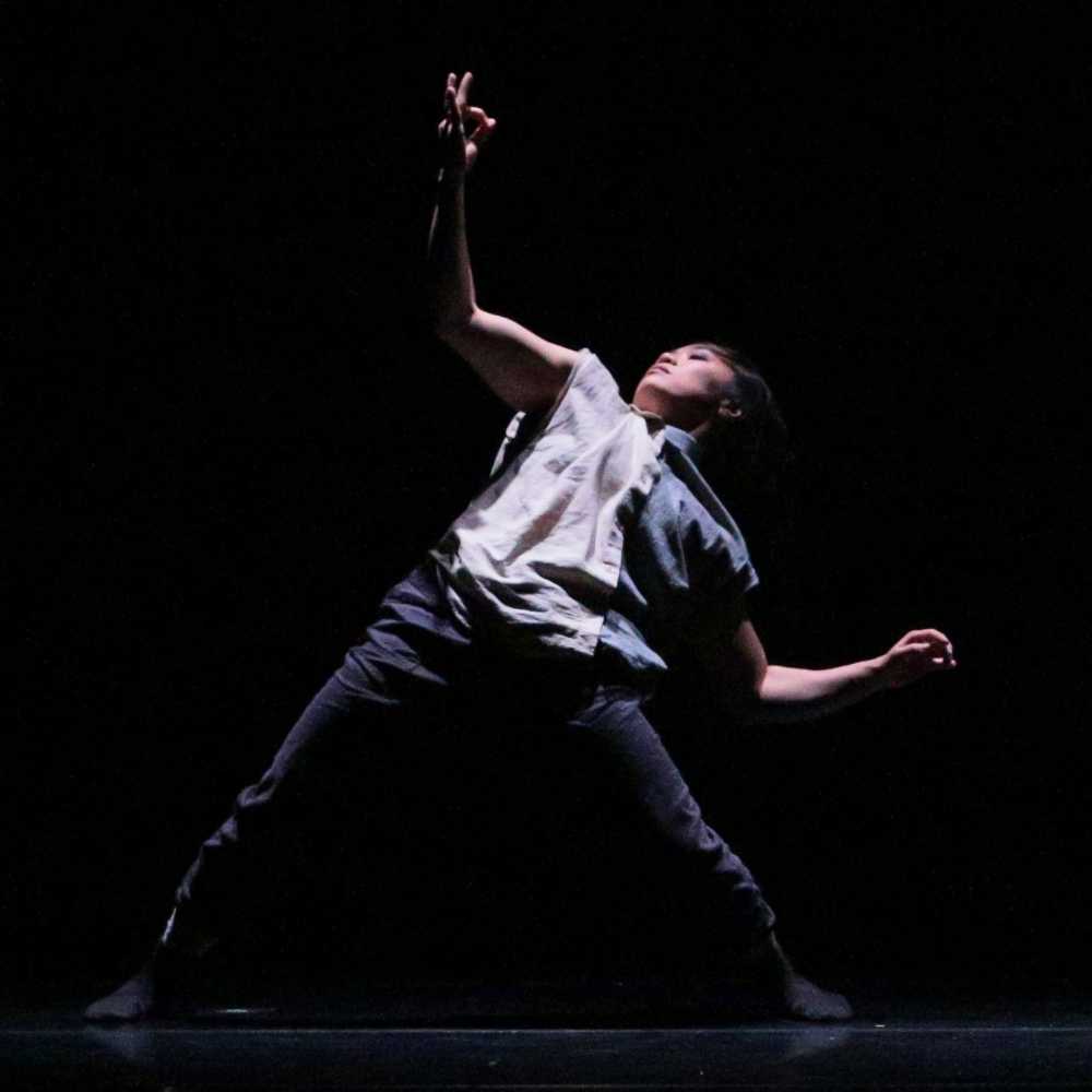 Waeli Wang dances on a dark stage