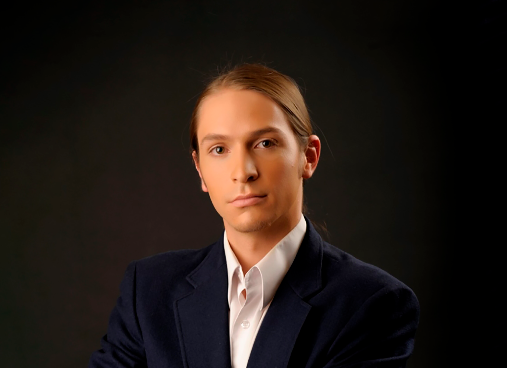 Close up professional portrait of a young man in a suit with hair pulled back