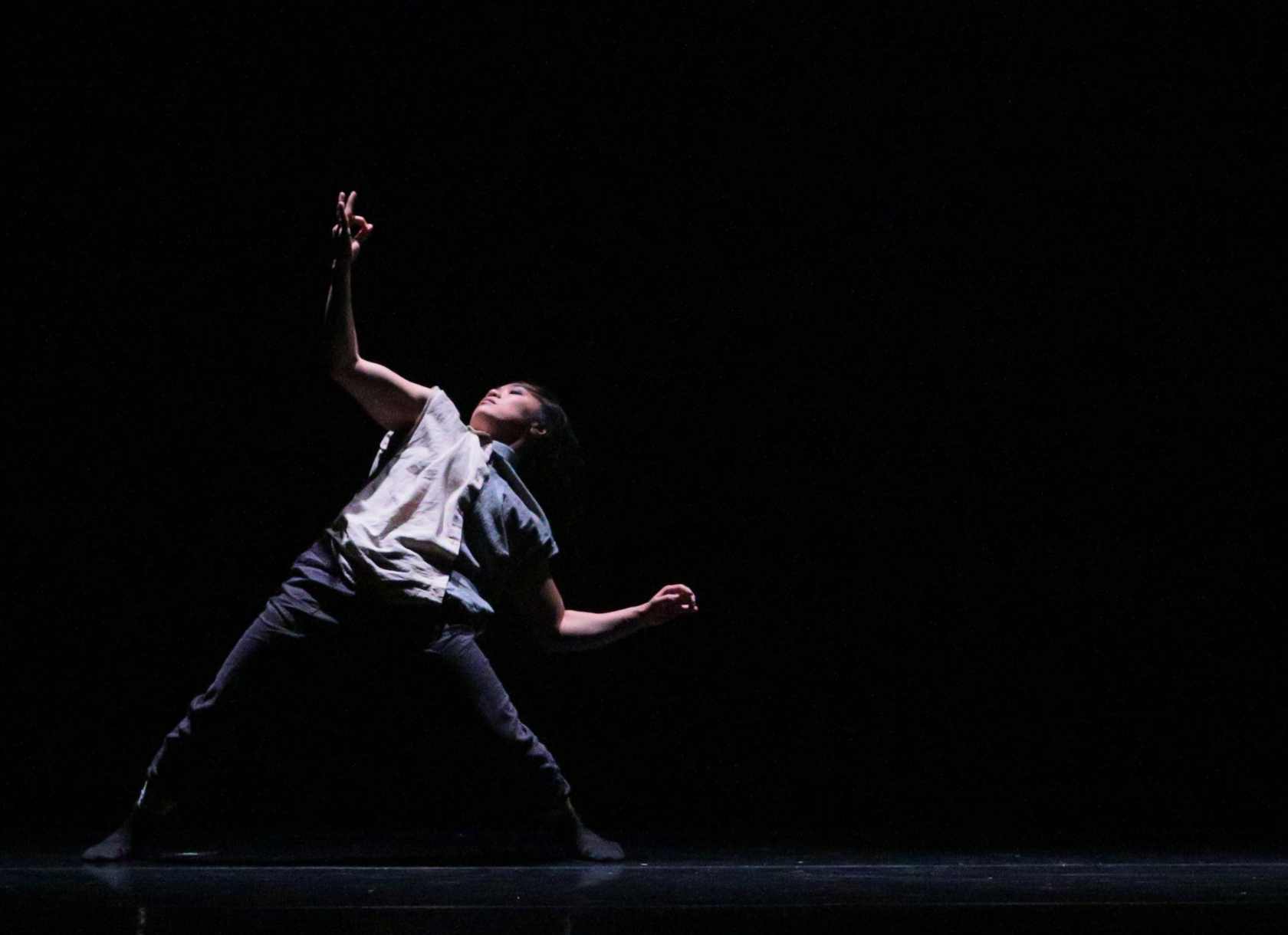 Waeli Wang dances on a dark stage